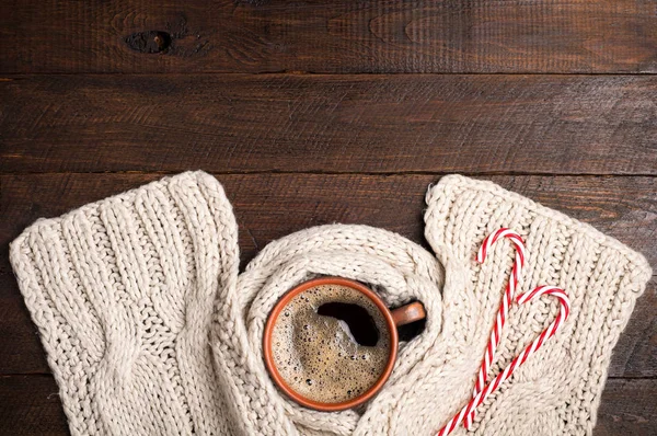 Xícara de café e lenço feito à mão de lã, bengalas doces na mesa de madeira. Natal fundo de inverno — Fotografia de Stock