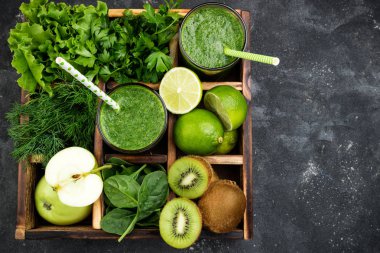 Yeşil smoothie karanlık beton masada malzemelerle. Sağlıklı bir diyet meyve ve sebze, üstten görünüm yüzlü