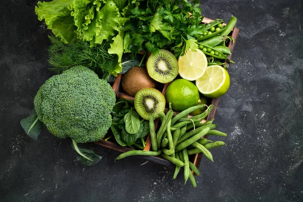 緑の野菜の背景。庭の新鮮な農産物。ブロッコリー、ほうれん草、キウイ、レタス、パセリ、ディル、暗いコンクリートのテーブル上にアスパラガス豆 — ストック写真