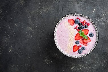 Çilek, çilek, yaban mersini, kızılcık, kuş üzümü ile güler yüzlü kase. Pembe yüzlü koyu arka plan üzerinde. Sağlıklı gıda ve diyet kavramı. Üstten Görünüm