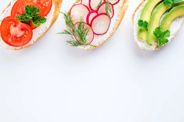 Mini-Sandwiches mit Frischkäse, Gemüse und Avocado. verschiedene Sandwiches auf weißem Hintergrund, Draufsicht. flache Lage — Stockfoto