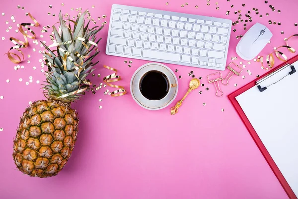 Platt lekmanna fashion feminina hemmakontor arbetsyta. Festlig kvinnliga bakgrund. Ananas, kaffekopp, gyllene konfetti och klipp på rosa bord — Stockfoto