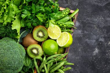 Yeşil sebzeler arka plan. Brokoli, ıspanak, kivi, marul, maydanoz, dereotu, kuşkonmaz fasulye karanlık beton masada. Taze Bahçe ürünler