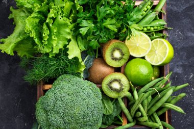 Yeşil sebzeler arka plan. Brokoli, ıspanak, kivi, marul, maydanoz, dereotu, kuşkonmaz fasulye karanlık beton masada. Taze Bahçe ürünler