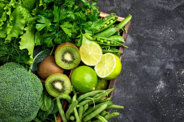 Yeşil sebzeler arka plan. Brokoli, ıspanak, kivi, marul, maydanoz, dereotu, kuşkonmaz fasulye karanlık beton masada. Taze Bahçe ürünler