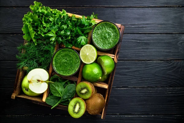 Koyu ahşap zemin üzerine yeşil smoothie. Sağlıklı güler yüzlü kokteyl. Yeşil sebze ve meyve. Sağlıklı gıda ve beslenme kavramı. Üstten Görünüm