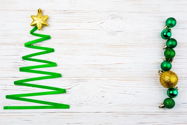 Christmas tree made from ribbon and christmas decorations on white wooden background. Copy space — Stock Photo, Image