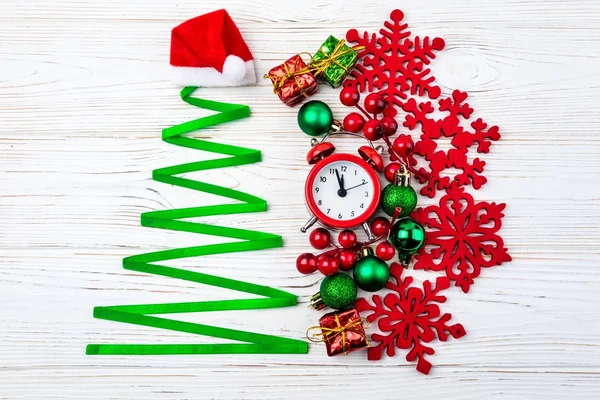 Kerstboom gemaakt van lint, kerst decoratie, geschenken en klok op witte houten achtergrond. — Stockfoto