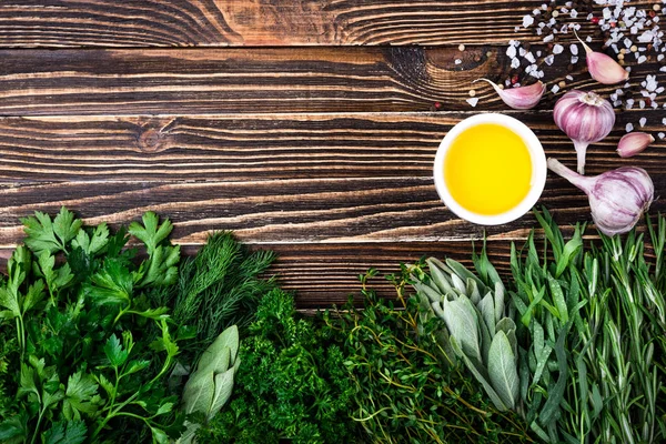 Erbe e spezie fresche, aglio, olio d'oliva su fondo di legno. Cibo sano e concetto di cucina. Erbe da giardino — Foto Stock