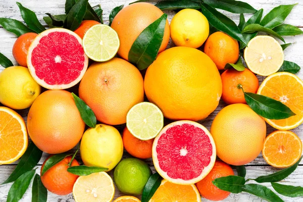 Owoce cytrusowe tła. Wyborem świeżych owoców cytrusowych z liści. Pomarańczy, grejpfruta, cytryny, limonki, mandarynki — Zdjęcie stockowe