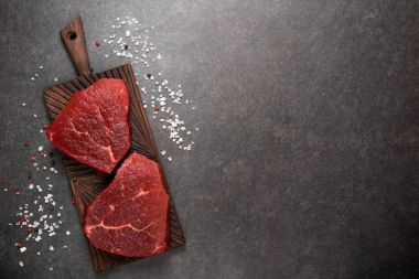 Çiğ et, sığır eti biftek ile koyu arka plan üzerinde üstten görünüm baharat.