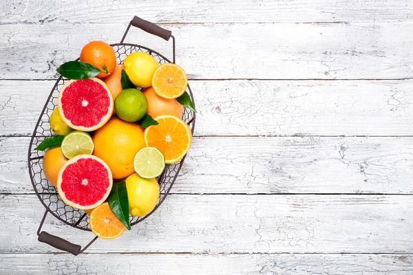 Fresh citrus fruits in basket. Orange, grapefruit, lemon, lime, tangerine. Assorted fresh citrus fruits with leaves — Stock Photo, Image