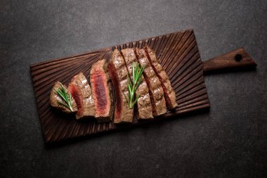 Kesme tahtası biberiye ve baharatlar ile sığır eti biftek. Izgara et az pişmiş biftek