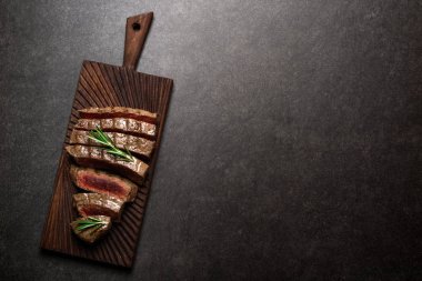 Kesme tahtası biberiye ve baharatlar ile sığır eti biftek. Izgara et az pişmiş biftek