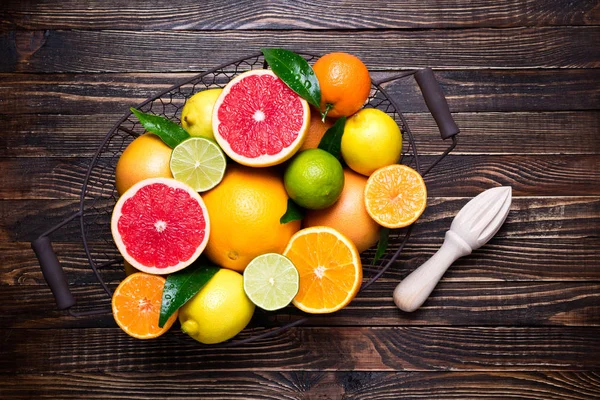 Frutas cítricas e fundo de suco de cítricos de cozinha. Frutos cítricos frescos variados com folhas. Laranja, toranja, limão, limão, tangerina na mesa de madeira — Fotografia de Stock