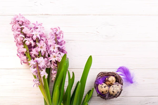 Latar belakang Paskah musim semi. Bunga dan sarang Hyacinth dengan telur di latar belakang kayu putih — Stok Foto