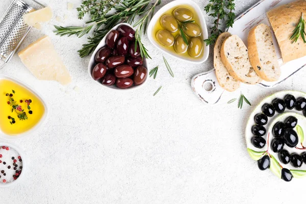 Snack mediterranei. Ciabatta pane, olive, formaggio, olio, erbe aromatiche e spezie su fondo bianco — Foto Stock