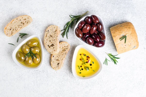 Středomořské občerstvení. Ciabatta chléb, olivy, olej, bylinky a koření na bílém pozadí — Stock fotografie