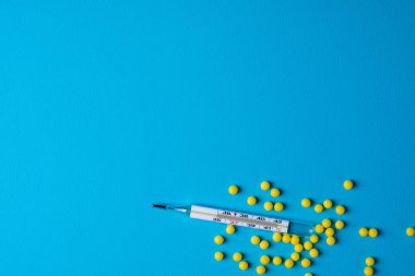 Tıbbi geçmişi. Termometre, hap mavi bir arka plan üzerinde. Tıp, sağlık, grip tedavileri kavramı