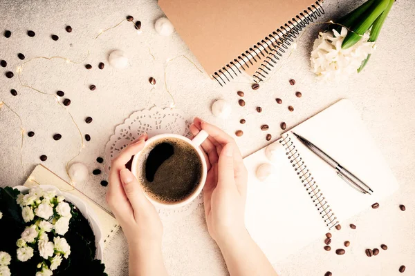 Kobiece ręce trzymając kubek kawy. Kawa, kwiaty, Notebooki i diody led, przytulne weekend koncepcja, widok z góry. Kobiecość tło, płaskie świeckich — Zdjęcie stockowe