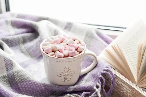 Tasse à café, livre ouvert, guimauve et plaid chaud sur un rebord de fenêtre en hiver. Petit déjeuner confortable à la maison — Photo