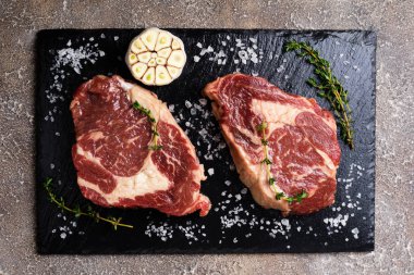 Çiğ et otlar ve baharatlar ile. Kekik ve sarımsak yemek pişirmek için kesme tahtası üzerinde ham sığır eti biftek