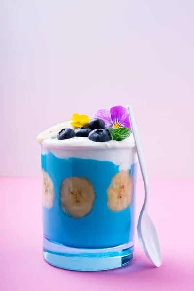 バナナやブルーベリー、パステル ピンクの背景に食べる花青のスムージー。熱帯健康スムージー デザート。健康的な朝食のコンセプト — ストック写真
