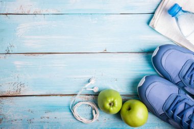 Düz yatıyordu spor ayakkabı, şişe su, elma, havlu ve kulaklık mavi ahşap zemin üzerinde. Sağlıklı yaşam, spor ve diyet kavramı