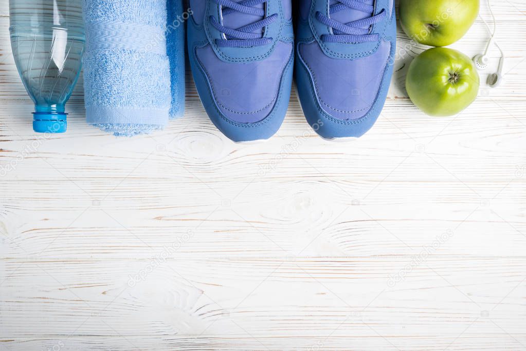 Flat lay sport shoes, bottle of water, apples, towel and earphones on white background. Sport equipment. Healthy lifestyle, sport and diet concept