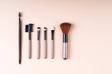 Bej renkli arka plan düz makyaj Kozmetik aksesuarlar yatıyordu. Kozmetik fırçalar kümesi. En az kompozisyon. Moda ve güzellik bloglama kavramı. Üstten Görünüm, kopya alanı