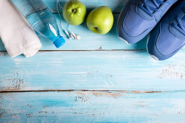 Flache Sportschuhe Wasserflasche Äpfel Handtuch Und Kopfhörer Auf Blauem Hintergrund — Stockfoto