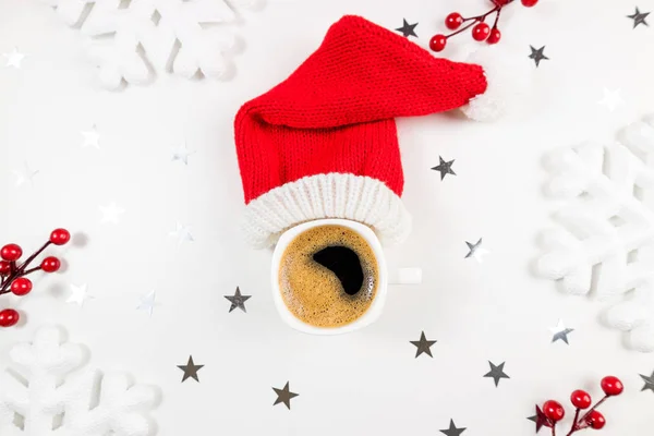 Christmas winter composition with coffee cup on white background. Coffee cup with red santa hat. Christmas, new year, holiday, celebration, festive coffee drink