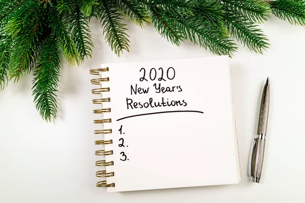 Rezoluția de Anul Nou 2020 pe birou. Obiectivele 2020 cu caiet, stilou și pom de Crăciun pe fundal alb. Scop, plan, strategie, schimbare, concept de idee — Fotografie, imagine de stoc