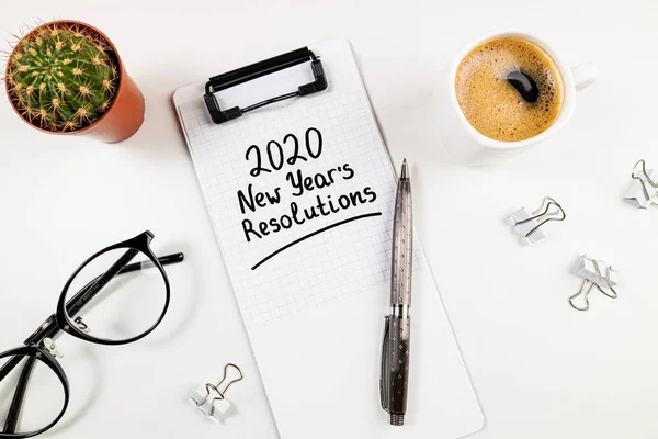 Oud en Nieuw resoluties 2020 op bureau. 2020 doelenlijst met notebook, koffiebeker en glazen op witte achtergrond — Stockfoto