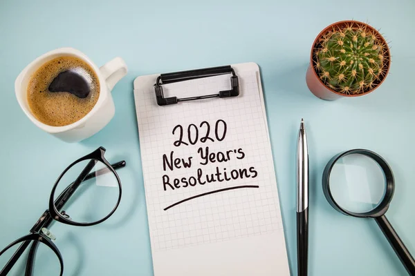Resoluções de ano novo 2020 na mesa. 2020 lista de metas com notebook, xícara de café e óculos em fundo azul. Objetivo, plano, estratégia, mudança, conceito de ideia — Fotografia de Stock