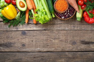 Sağlıklı bir geçmişi var. Tahta masada taze sebze, meyve, fasulye ve mercimek. Vejetaryen yemeği. Sağlıklı yemek, diyet, vegan ve sağlıklı beslenme konsepti. Üst görünüm, alanı kopyala