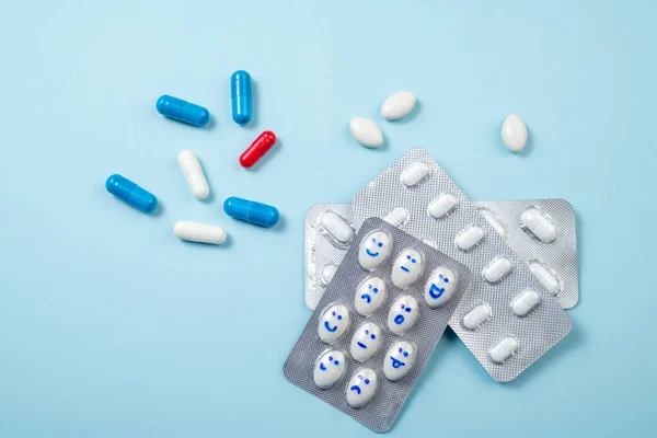 Pharmaceutical medicine background. Blister of funny pills with smiles faces on blue. Health care, daily pills, antidepressants, medicine, treatment concept. Copy space