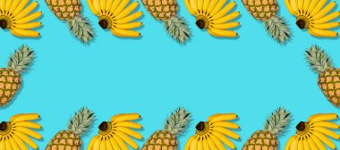 Mavi arka planda taze sarı muz ve ananas renkli meyve deseni. Tropik meyve çerçevesi. Minimum yaz yemeği konsepti. Uzun biçim, üst görünüm, boşluk kopyala