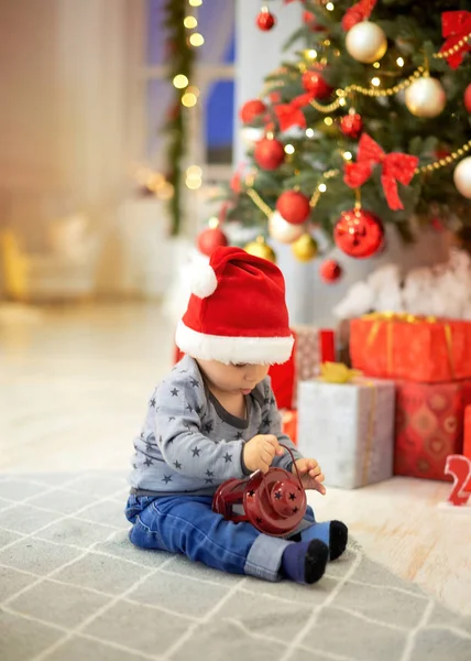 Petit garçon assis sur un fond d'arbre de Noël — Photo