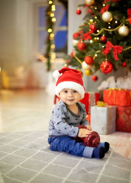 küçük çocuk Noel ağacı bir arka plan üzerinde oturan