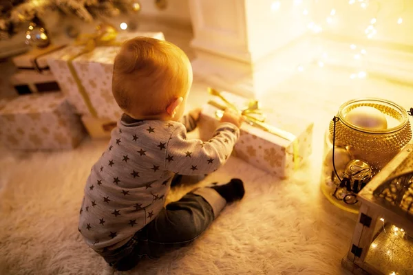 Niño sentado en un árbol de Navidad — Foto de Stock