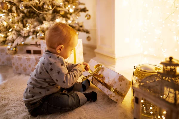 Μικρό αγόρι κάθεται σε ένα χριστουγεννιάτικο δέντρο — Φωτογραφία Αρχείου