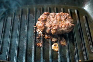 Bir kalbur tava ızgara sığır eti hamburger köftesi