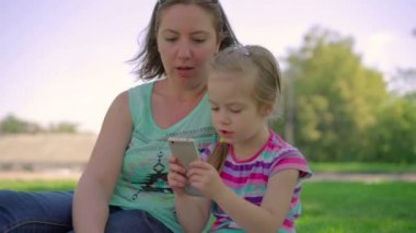 Anne ve kızı parkta telefonda bir oyun oynamak.
