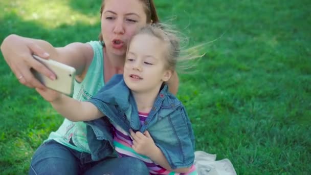 Meisje met moeder rustend in een park, maken selfie. — Stockvideo