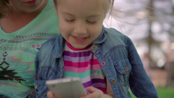 Η μητέρα βοηθά την κόρη του ένα παιχνίδι στο τηλέφωνό σας. — Αρχείο Βίντεο