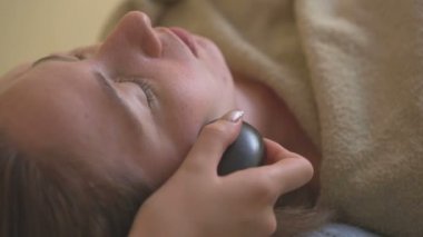 Genç kadının sıcak taş masaj spa yapması.