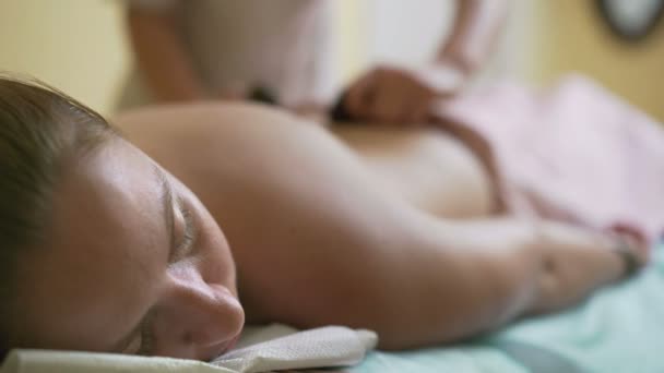 Jovem, bela mulher massagista faz massagem com pedras quentes . — Vídeo de Stock