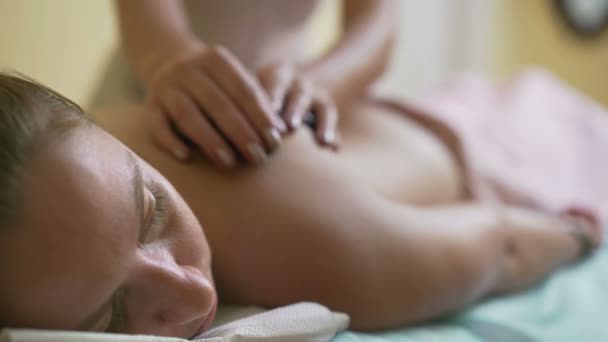 Jovem, bela mulher massagista faz massagem com pedras quentes . — Vídeo de Stock