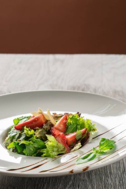 Yeşil salata, peynir ve çilek balzamik sos ile.